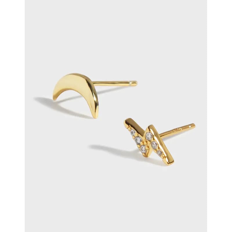 Polished gold-tone crescent and crystal-star stud earrings on a light background.
