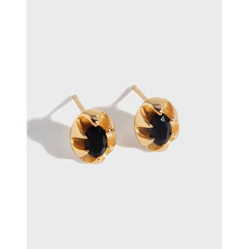 Gold-tone flower-shaped stud earrings with a black center stone and a polished finish.