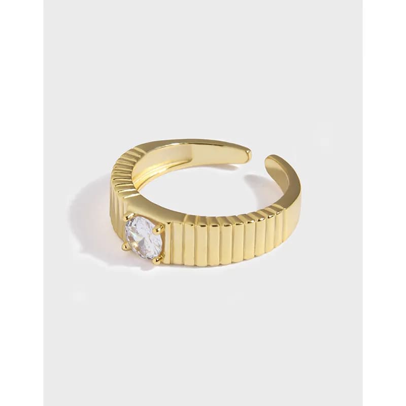 Gold-tone ribbed ring with a single clear stone set in four prongs