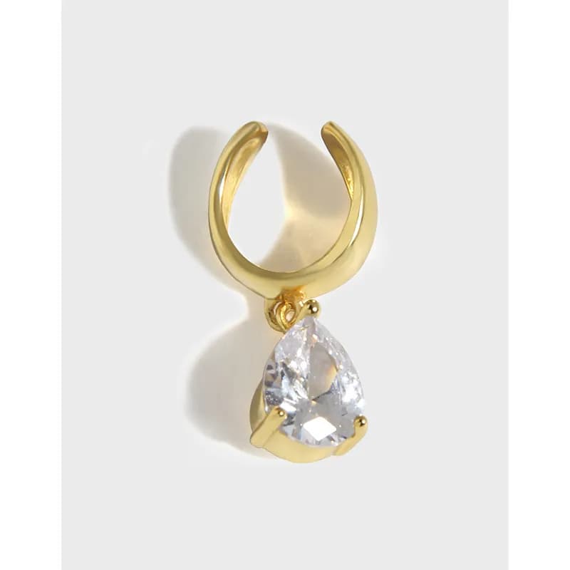 Open gold-tone hoop earring with a teardrop crystal pendant hanging below.