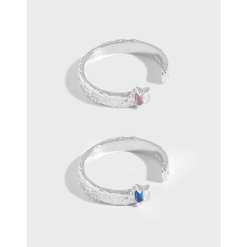 Two open-ended textured silver rings with pink and blue enamel accents on the tips.