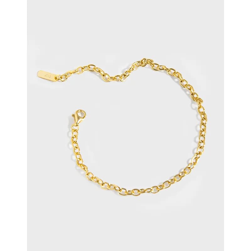 Polished sterling silver cable chain bracelet with a small tag charm and lobster clasp laid flat.
