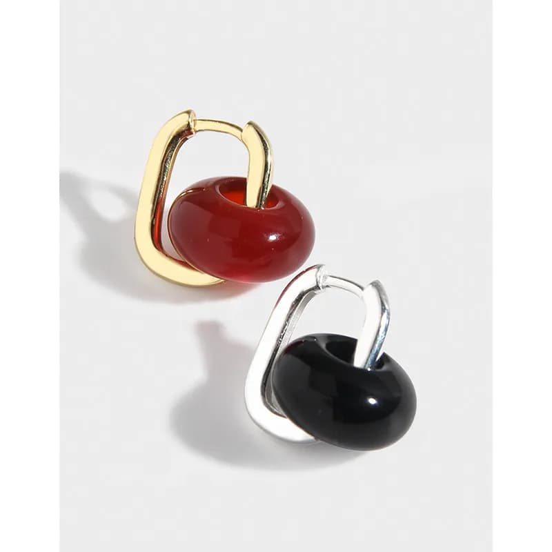 Close-up of two-tone bead hoop earrings: gold-plated and silver hoops with glossy red and black beads.
