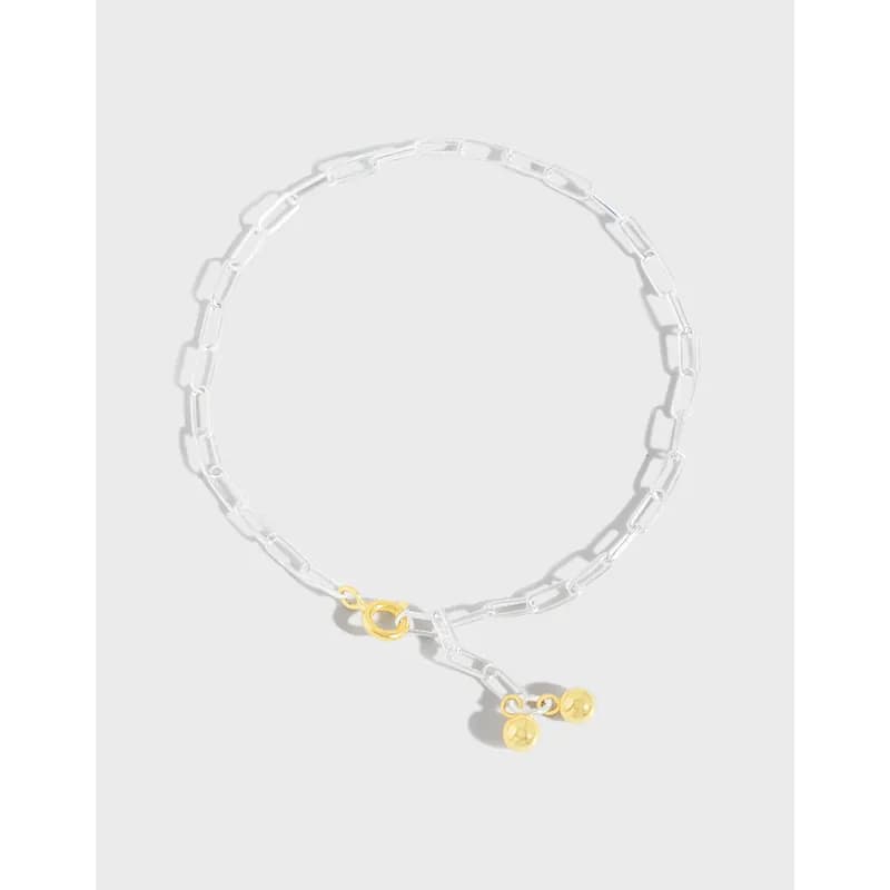 Polished sterling silver rectangular-link bracelet with a gold-tone toggle clasp and dangling gold spheres at the ends.