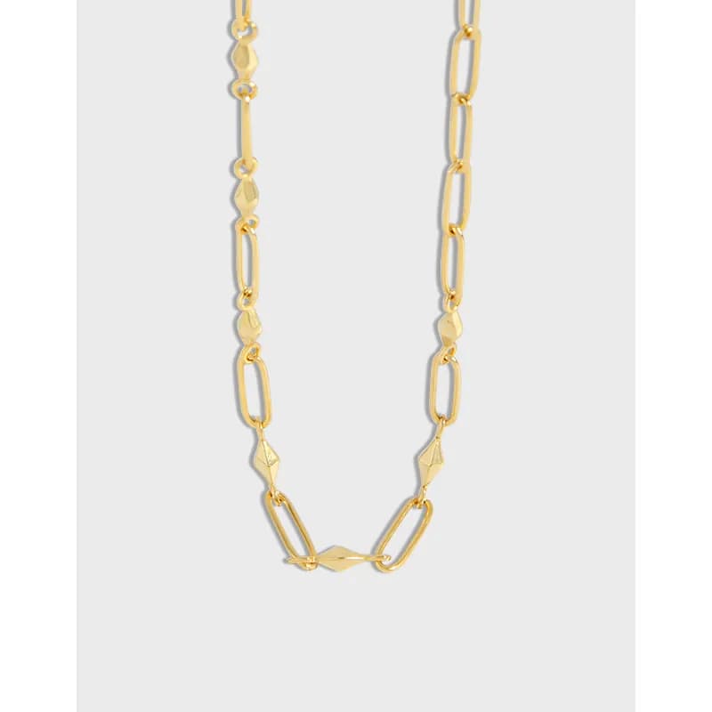 Close-up of a polished sterling silver geometric-link necklace with alternating elongated and faceted links on a light background.