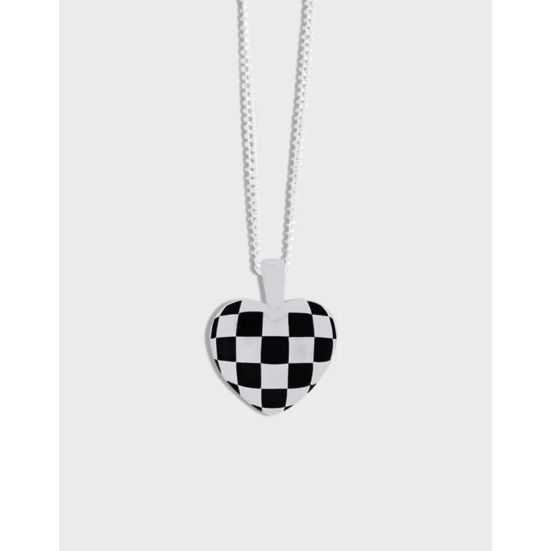 Polished sterling silver heart pendant with a black-and-white checkerboard pattern on a delicate chain.