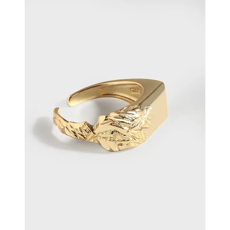 Polished sterling silver ring with a textured leaf motif wrapping across the front.