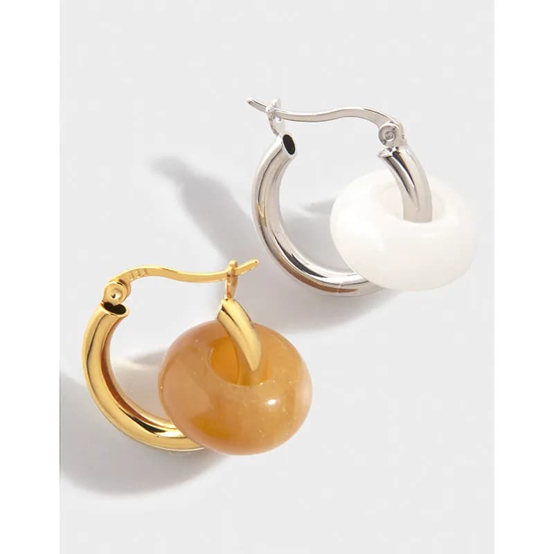 Pair of polished hoop earrings, silver with white donut bead and gold with amber donut bead.
