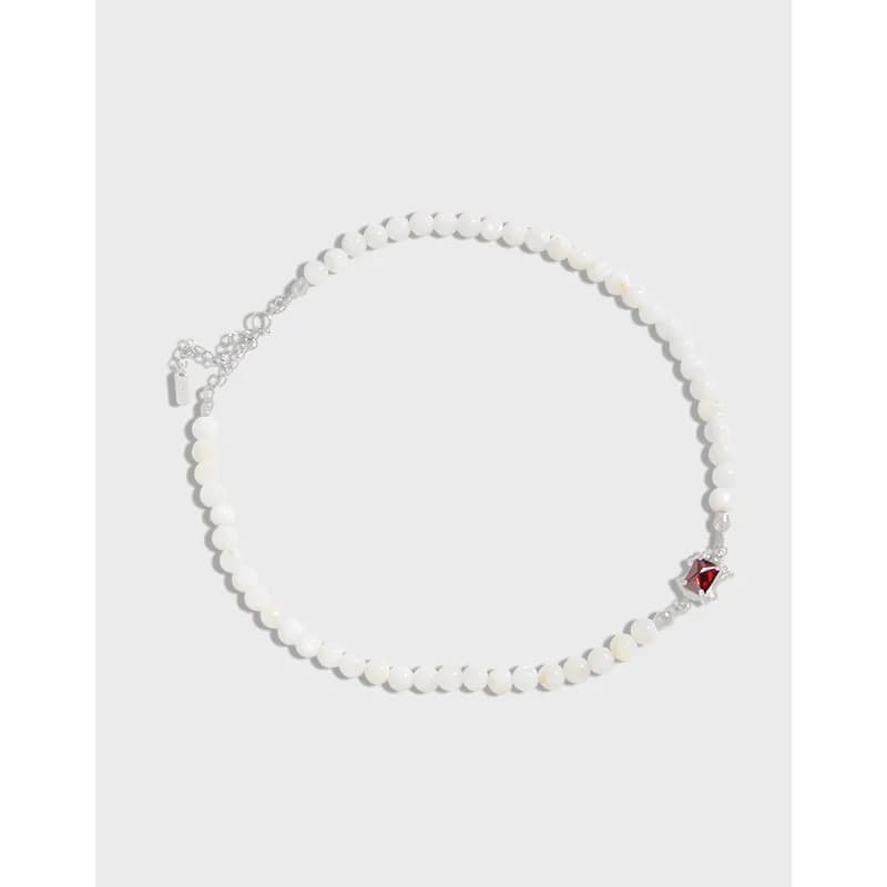 Beaded sterling silver necklace with a small red gemstone accent near the clasp.