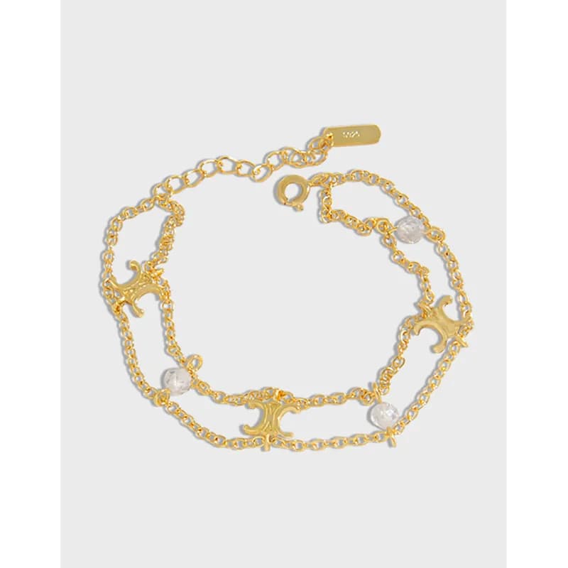 A polished sterling silver bracelet with crescent charms and small beads laid out on a light background.