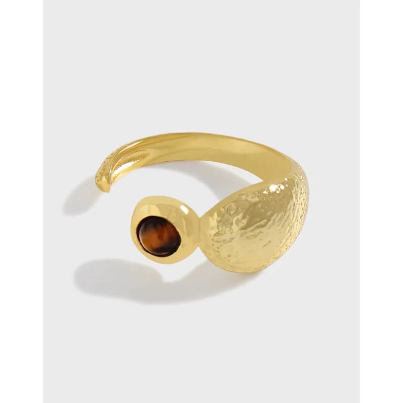 Open-ended gold-tone ring with a textured crescent and small bezel-set dark stone