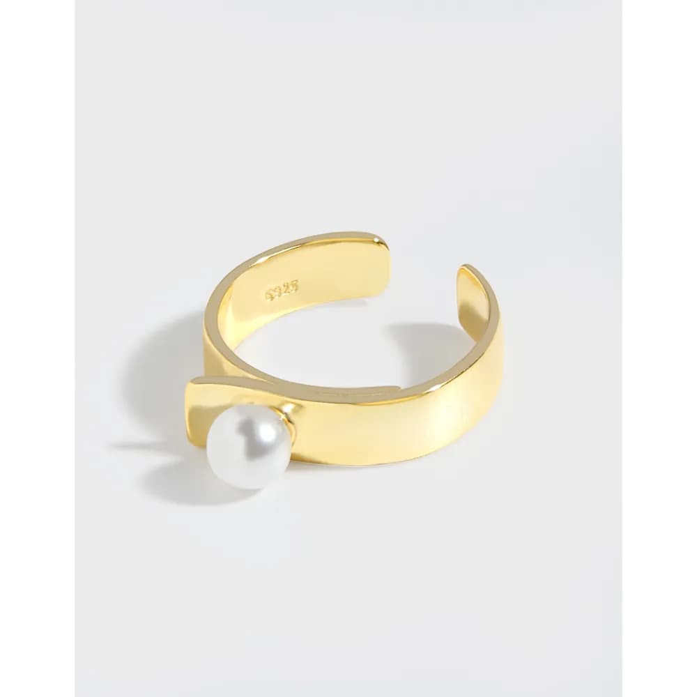Polished gold-tone ring with an open band and a single white pearl at the front.
