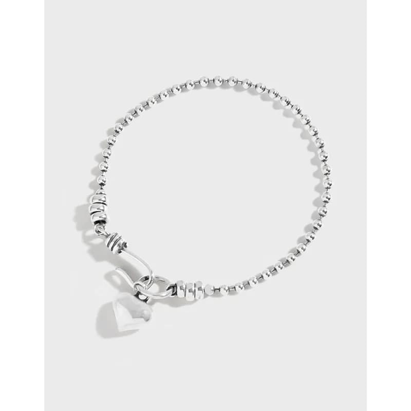Sterling silver beaded bracelet with a heart charm and curved clasp, shown on a white backdrop.