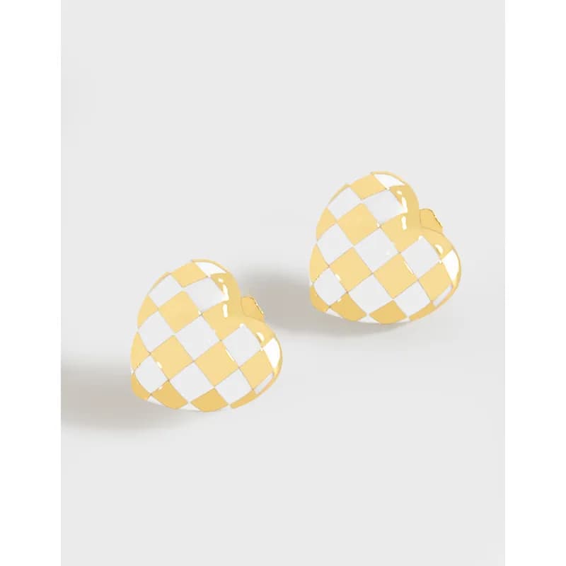 Two heart-shaped earrings with a yellow and white checkerboard pattern in polished metal.