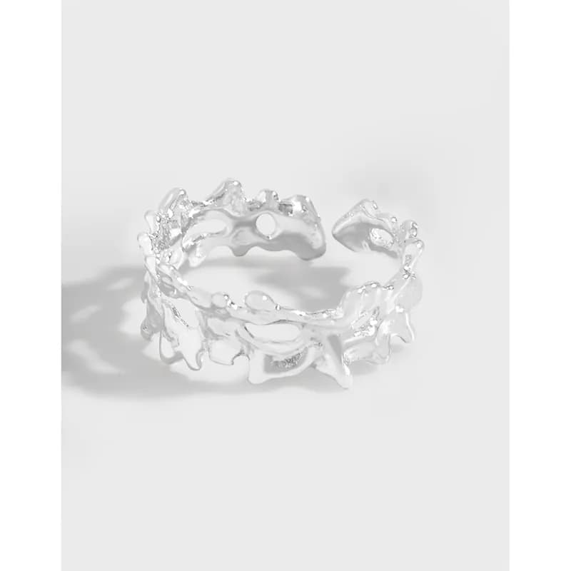 Matte sterling silver ring with irregular organic edges and openwork texture on a white background.