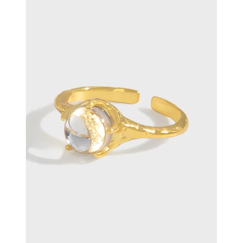 Open adjustable ring with a round clear stone set in a bezel on a gold-tone band.