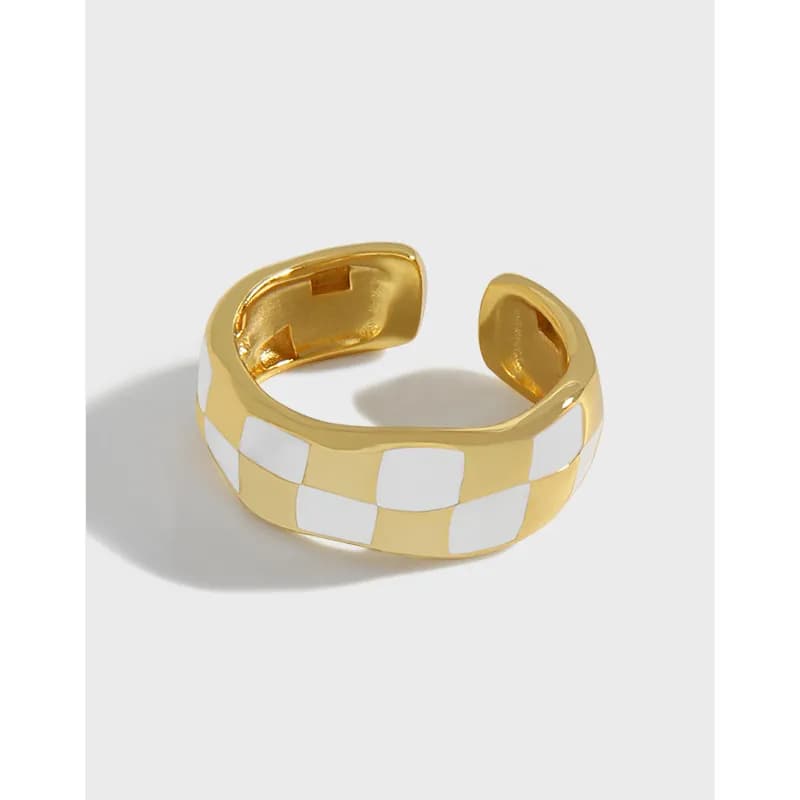 Open, wide ring with a gold-tone finish and white checkerboard enamel pattern