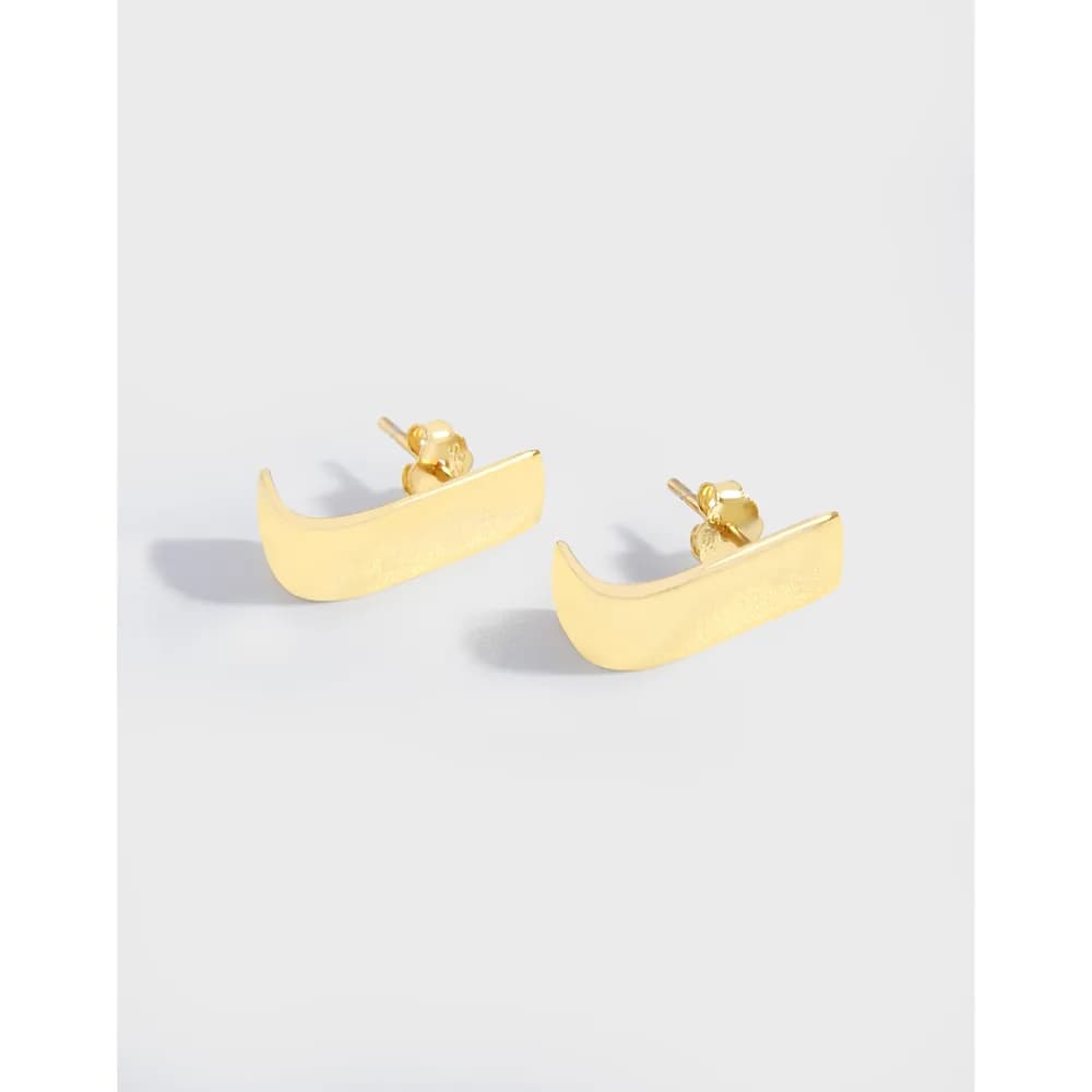 Polished curved gold-tone bar stud earrings with a crescent shape on a white background.