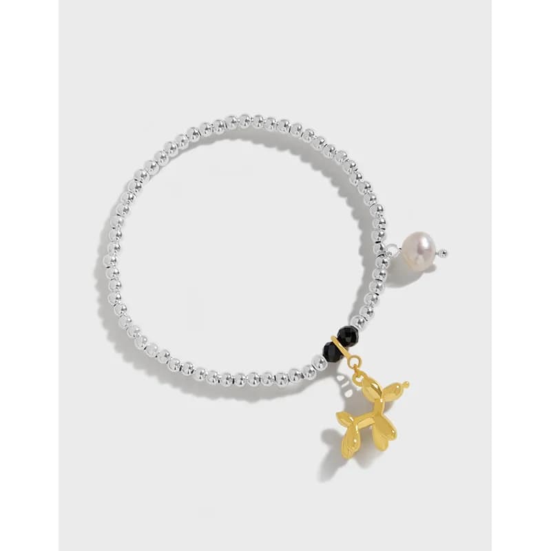 Close-up of a silver beaded bracelet with a gold butterfly charm and a pearl accent on the clasp