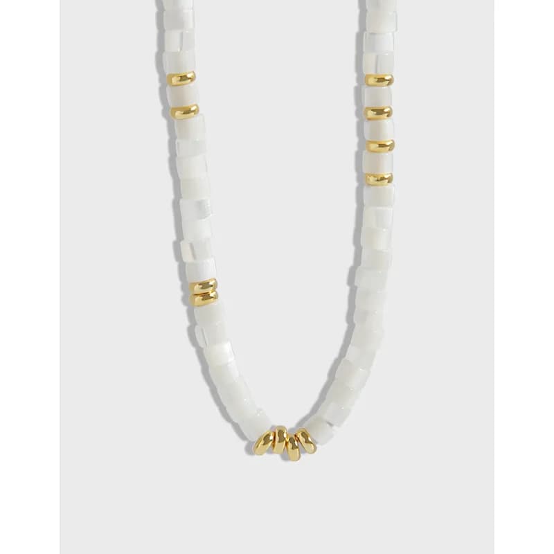 Polished sterling silver necklace with white square beads and gold spacers, shown with a small gold bead cluster at the center