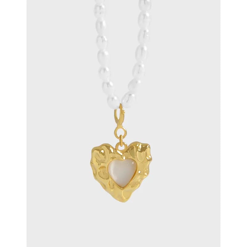 Polished necklace with a textured gold-tone heart pendant and white center on a bead-like chain.