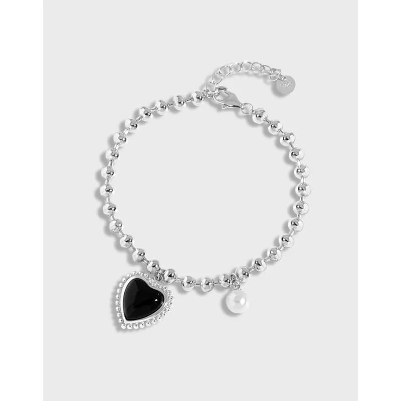 Silver beaded bracelet with a black heart pendant and a small white pearl charm