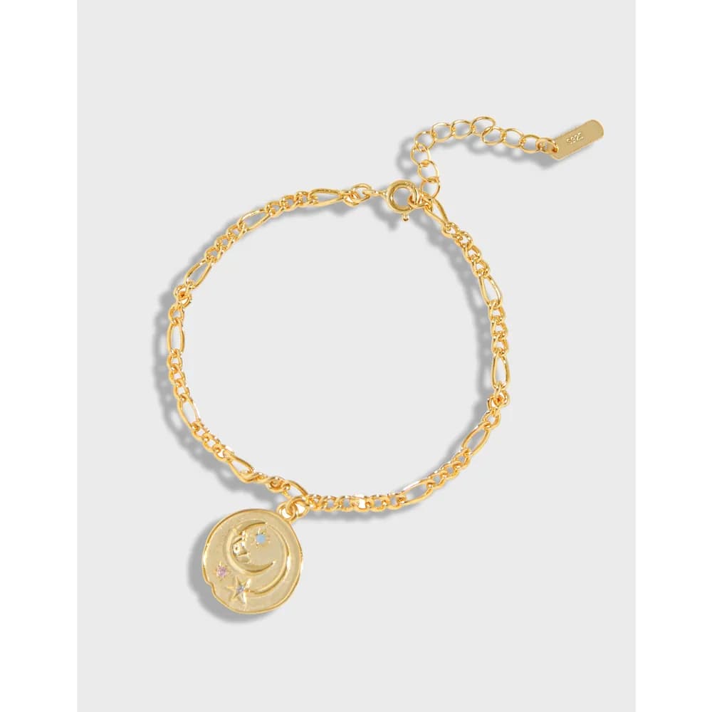 Polished silver bracelet with a round moon and star pendant on a delicate chain.