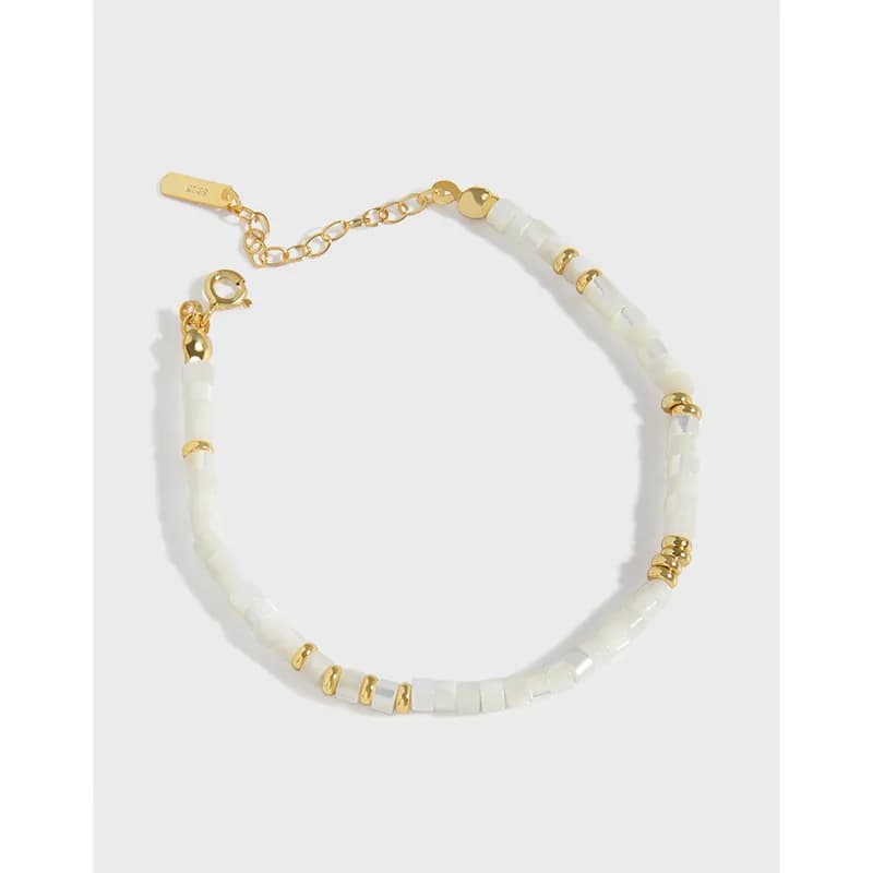 Polished sterling silver bracelet with white cube beads and gold spacers, shown with an adjustable clasp