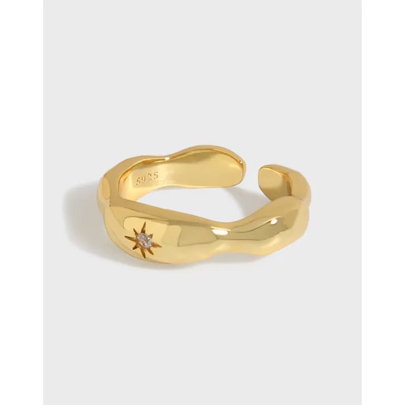 Polished sunburst ring with a small gemstone set in a curved, wrap-around band.