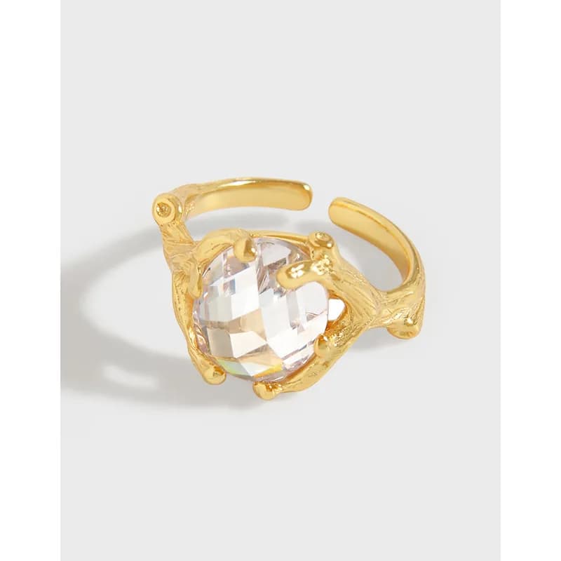 Open-ended sterling silver ring with a large faceted crystal held by claw-like prongs.