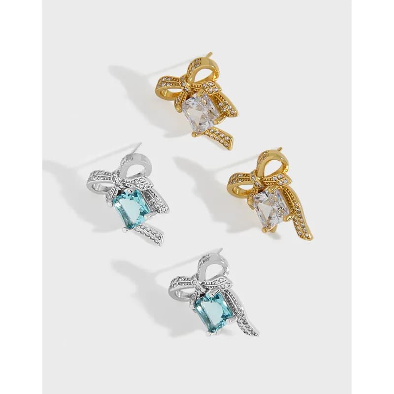 Polished silver bow earrings with a square-cut center stone and pavé detailing