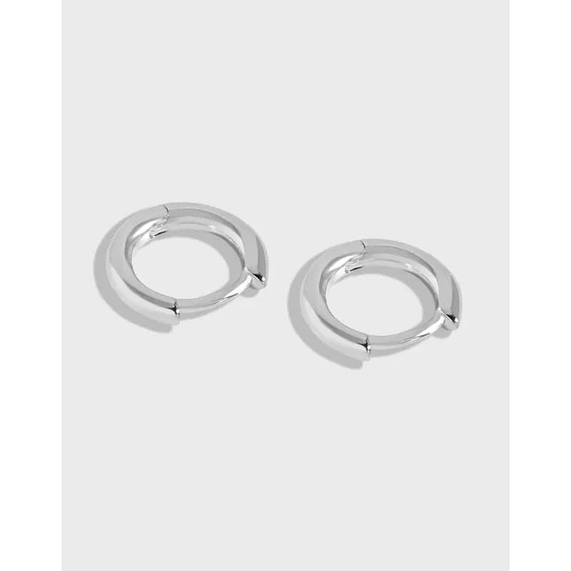 A pair of polished silver hoop earrings with hinged closures displayed on a light gray background.