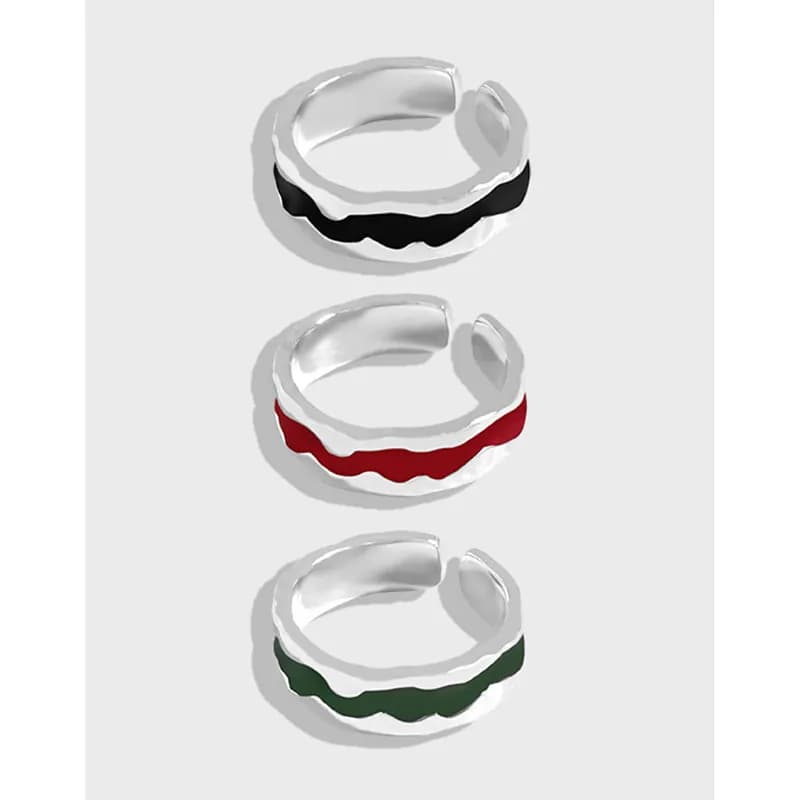 Three sterling silver rings with colorful wavy enamel stripes in black, red, and green