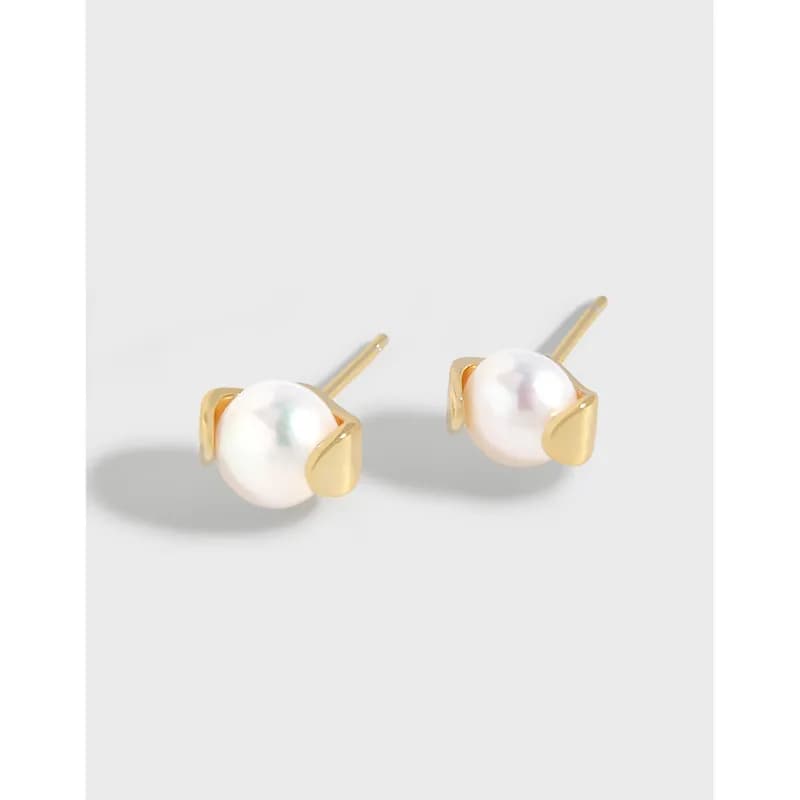 Pair of pearl stud earrings with gold-tone bezels set on a silver posts