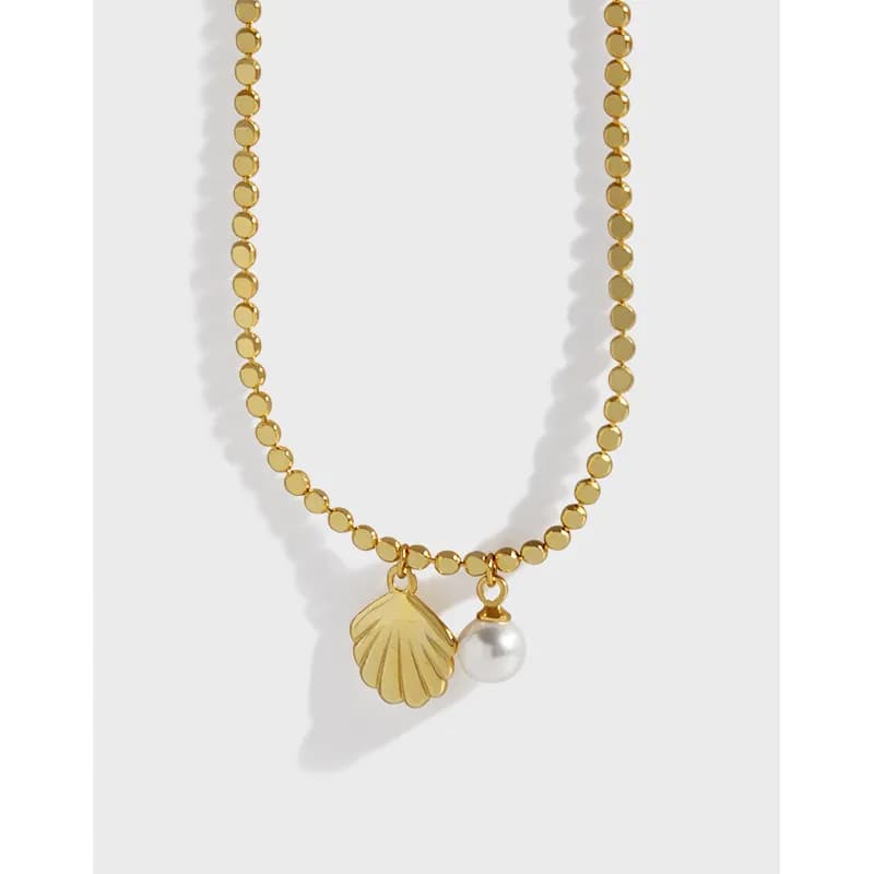 Beaded gold-tone shell and pearl pendant necklace shown on a white background.