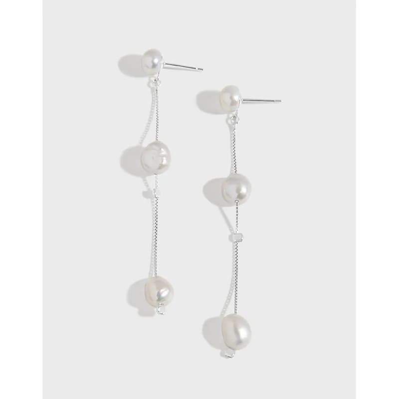 Long silver chain earrings with multiple pearls suspended along the chain, attached to a small pearl stud.