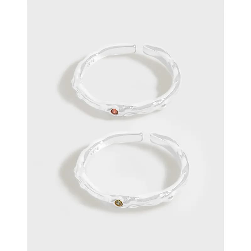 Two polished sterling silver hammered hoop rings with colored stones on the outer side, open at the ends.