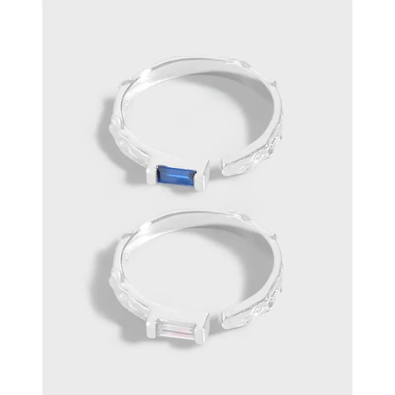 Two polished sterling silver rings with rectangular baguette stones set horizontally on a textured band
