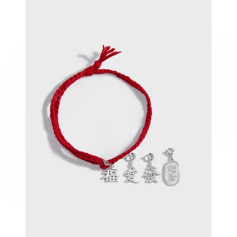 Red braided cord bracelet with four silver Chinese character charms and a silver tag on a light background.