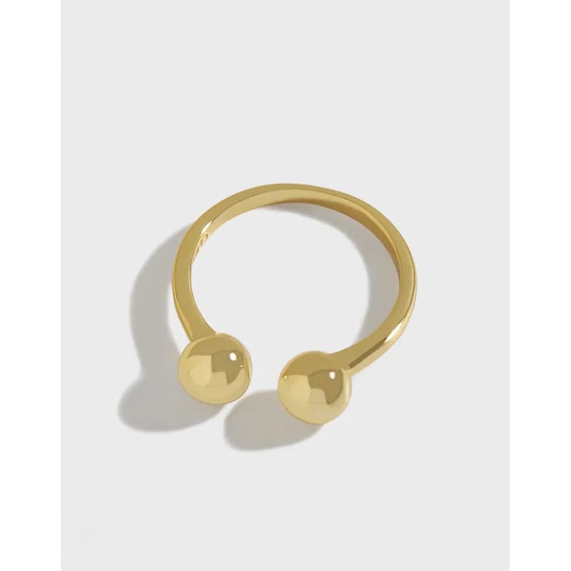 Polished sterling silver open ring with two spherical ends displayed on a light background.