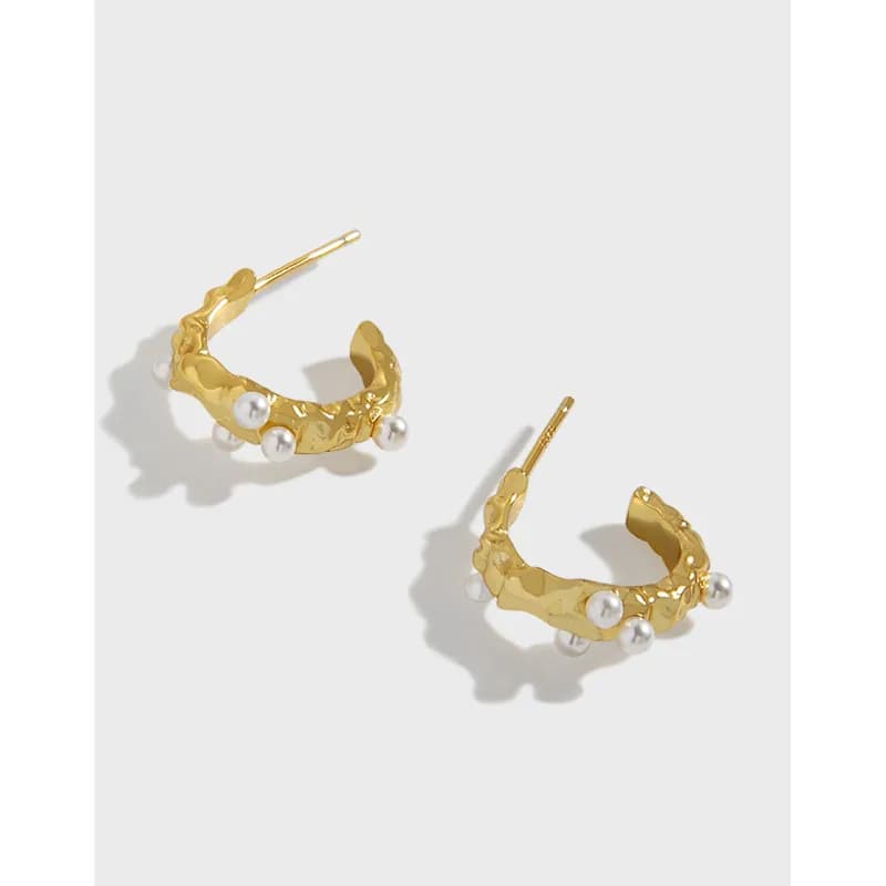 Pair of pearl-accênted hoop earrings with a gold-toned textured finish and pearl drops on a light background.