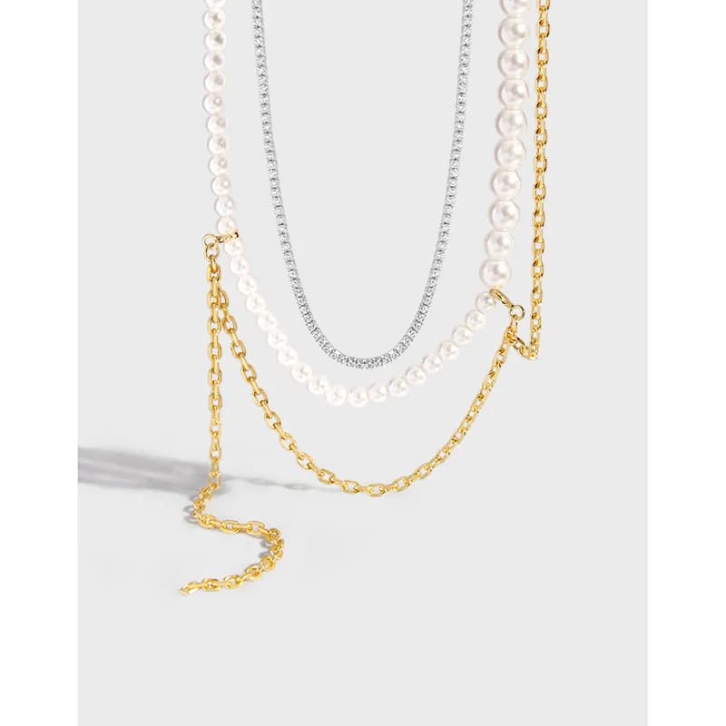 Three-layer necklace with a pearl strand, silver pavé chain, and gold-tone chain cascading together.