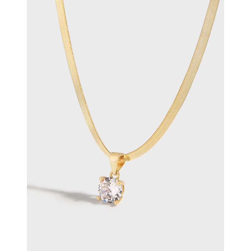 Close-up of a polished sterling silver necklace with a round clear gemstone pendant in a four-prong setting