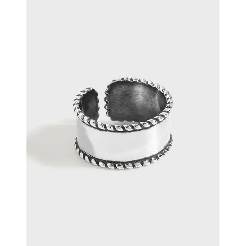 Wide sterling silver ring with brushed center and rope-edged borders on an open-back band.