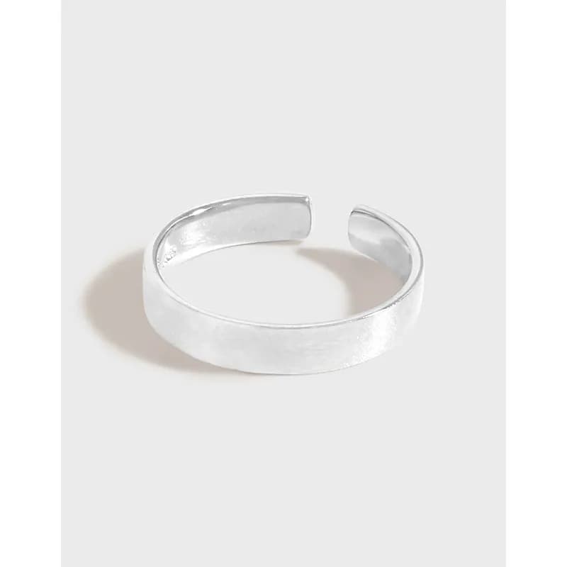 Open, wide polished sterling silver cuff ring displayed on a light neutral background.