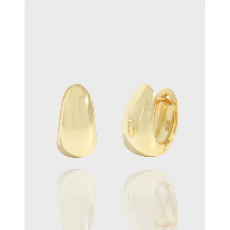 Close-up of polished curved gold-tone hoop earrings with hinged latch-back closure.