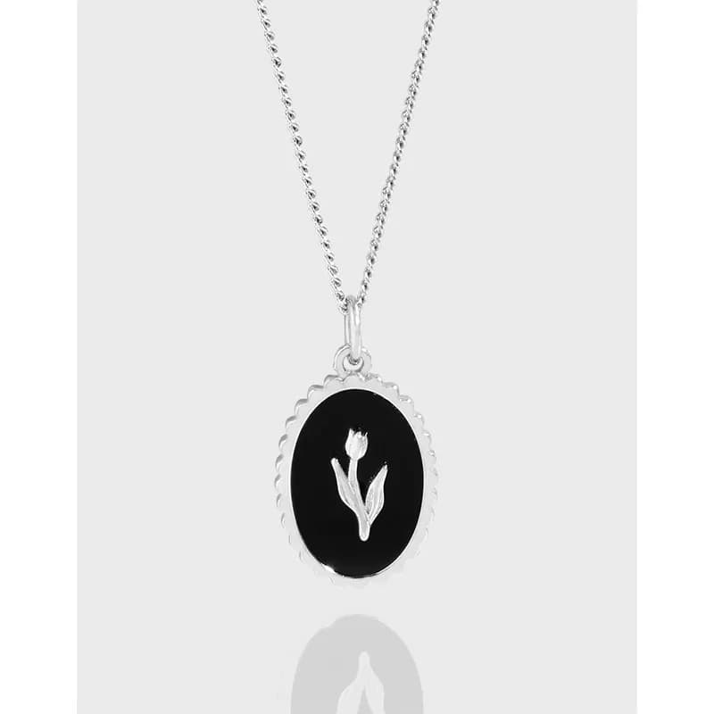 Sterling silver necklace with an oval black enamel pendant featuring a silver tulip motif on a polished chain.