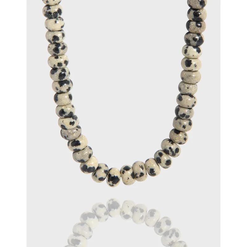 Polished dalmatian jasper bead necklace on a white background