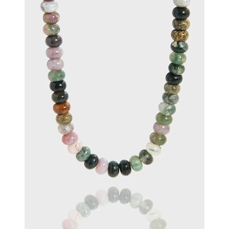 Close-up of a polished multicolor agate bead necklace with round stones in green, pink, and brown hues