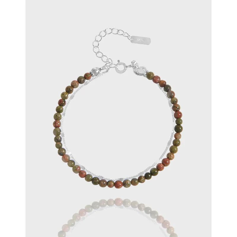 Sterling silver bracelet with earth-tone round beads and a thin chain on a light background.